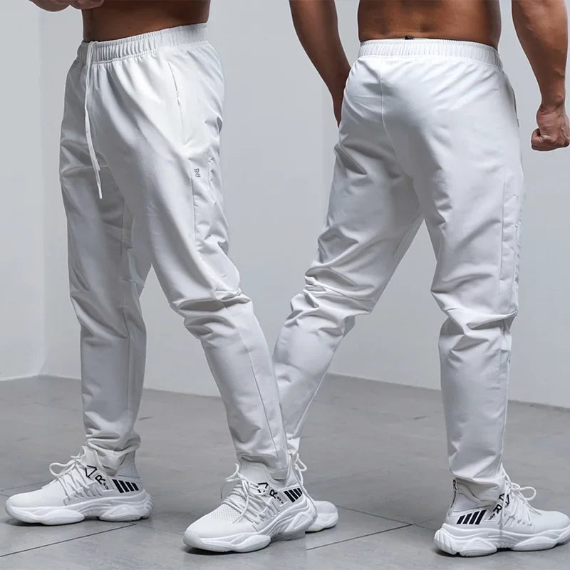 Two people wearing white jogger pants and white sneakers on a light gray background