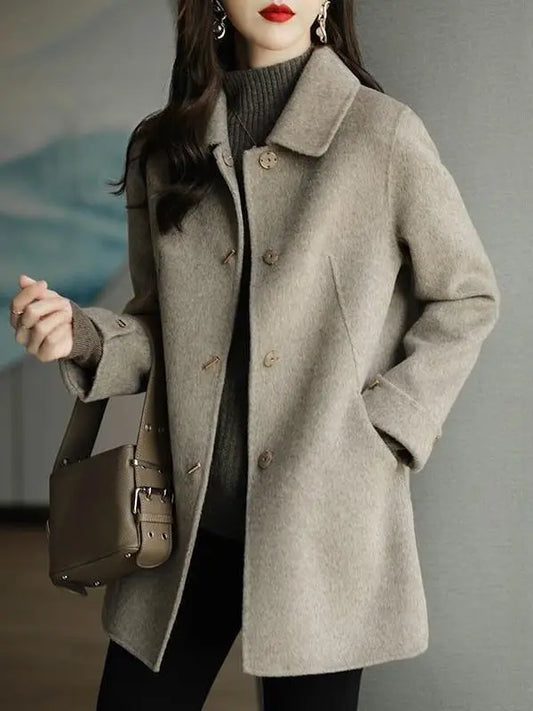 Woman wearing a gray coat with a blurred background