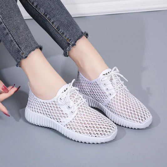 White mesh sneakers worn with gray jeans on a light gray background