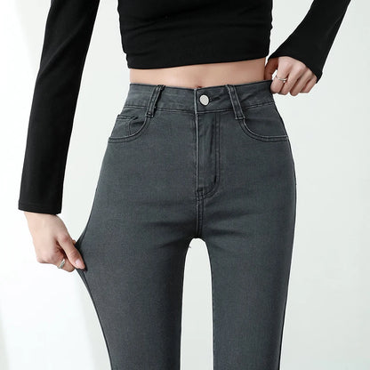 Person wearing high-waisted dark gray jeans with a plain background