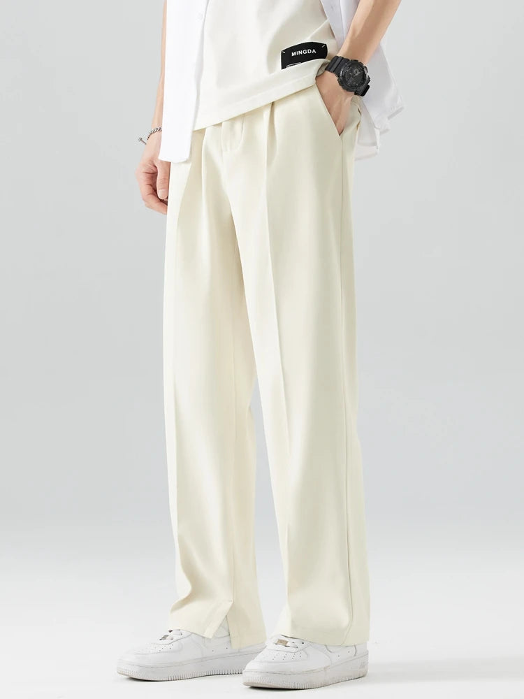 Person wearing light-colored pants and a white shirt on a plain background