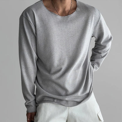 Person wearing a gray long-sleeve shirt and white pants on a gray background