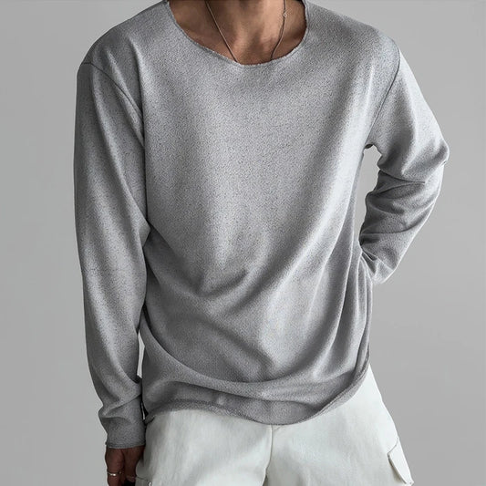 Person wearing a gray long-sleeve shirt and white pants on a gray background