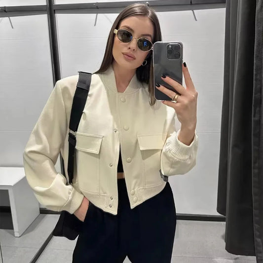 Woman taking a mirror selfie wearing a cream jacket and sunglasses.