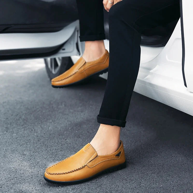 Person wearing brown loafers sitting on a car, with a focus on the shoes.
