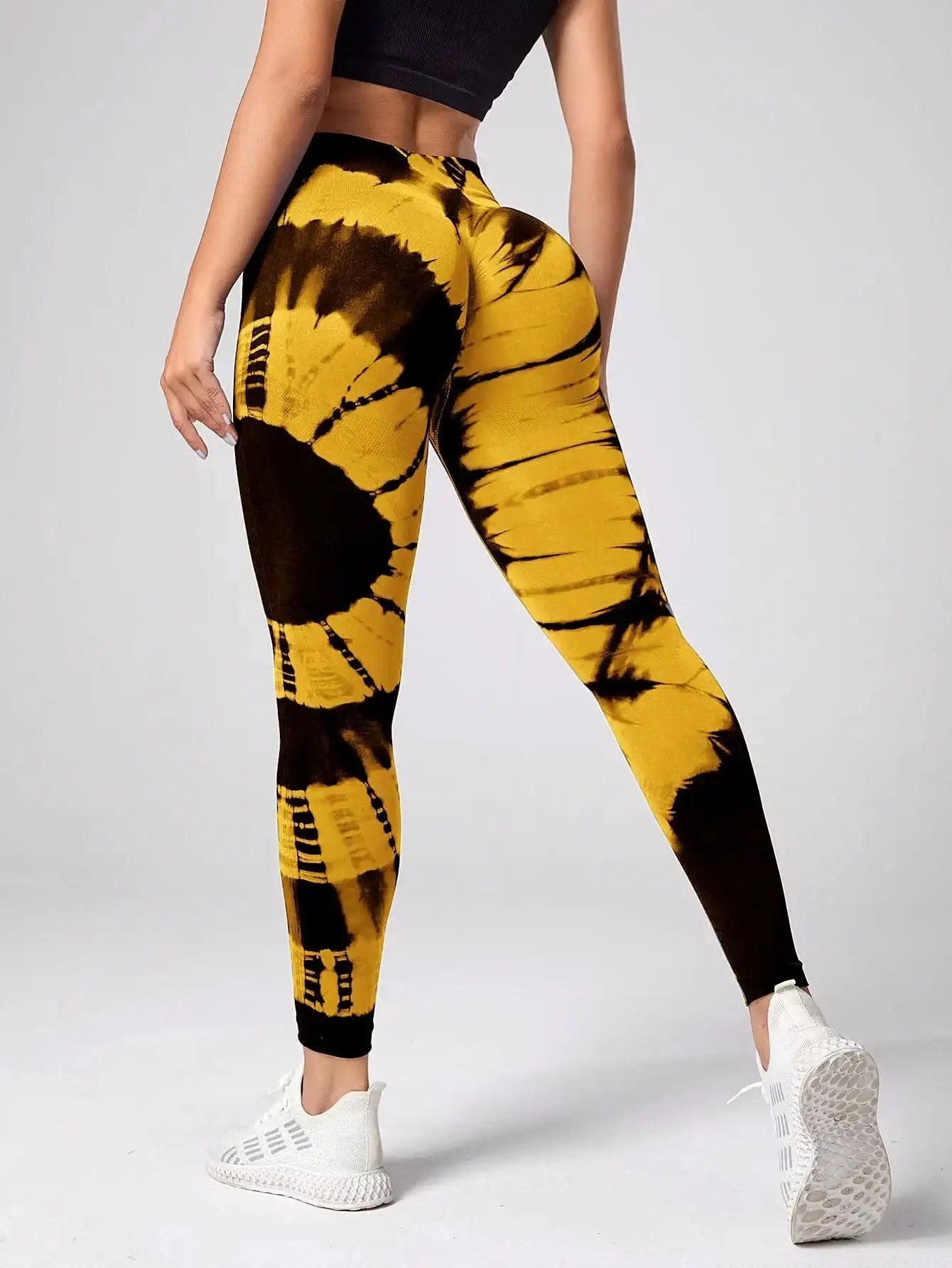 Yellow and black tie-dye leggings worn by a person on a gray background