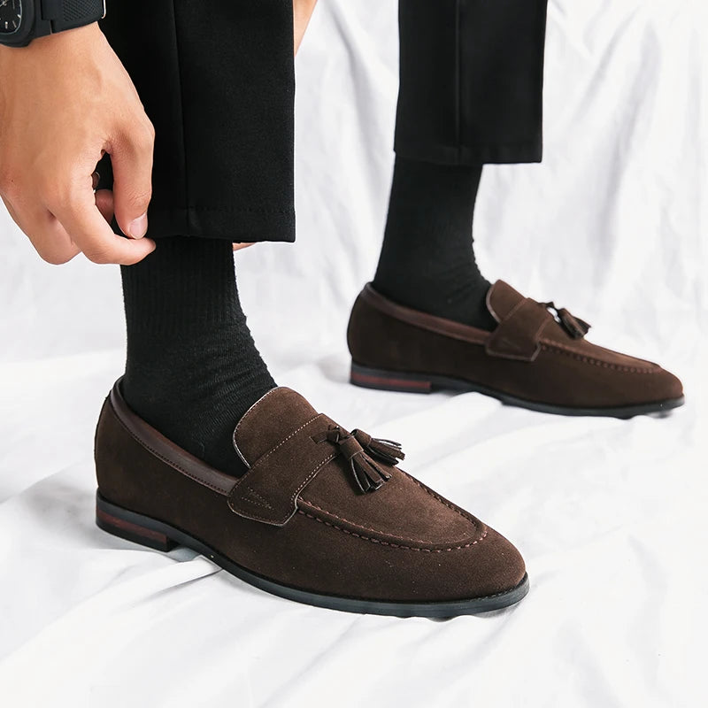 Brown loafers with tassels worn by a person on a white background