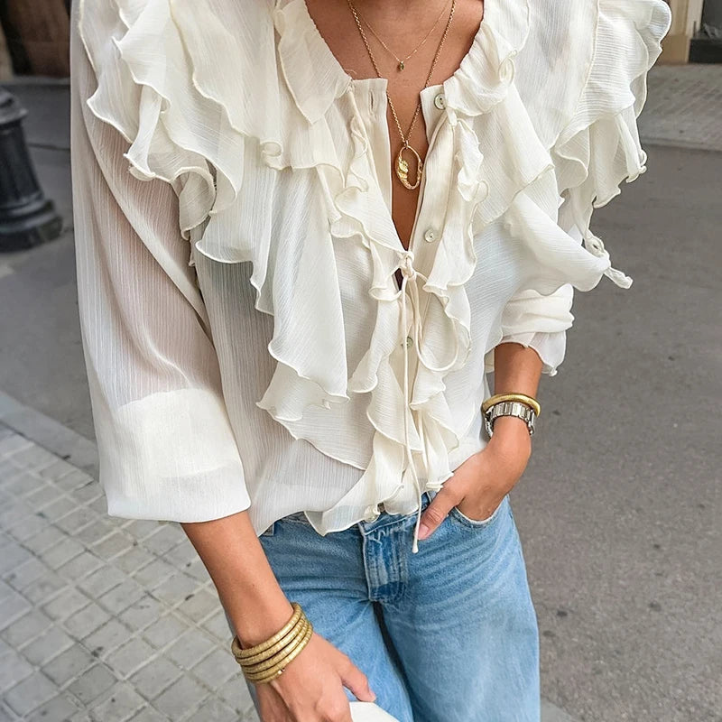 White ruffled blouse with blue jeans on a blurred street background