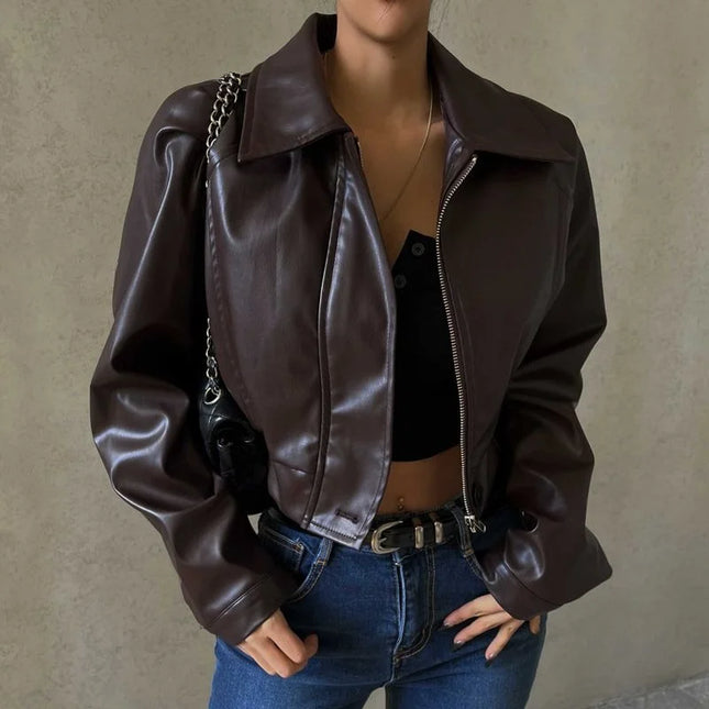 Person wearing a brown leather jacket and blue jeans against a neutral background