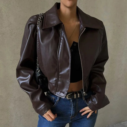 Person wearing a brown leather jacket and blue jeans against a neutral background