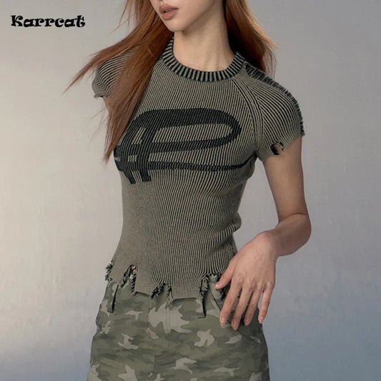 Woman wearing a green ribbed knit top and camouflage pants on a plain background