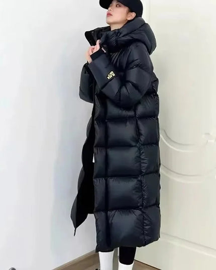 Person wearing a long black puffer coat against a white background