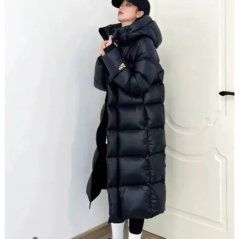 Person wearing a long black puffer coat against a white background
