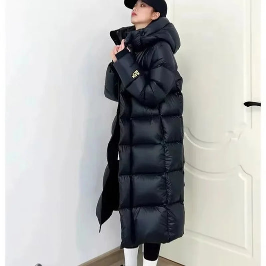 Person wearing a long black puffer coat against a white background