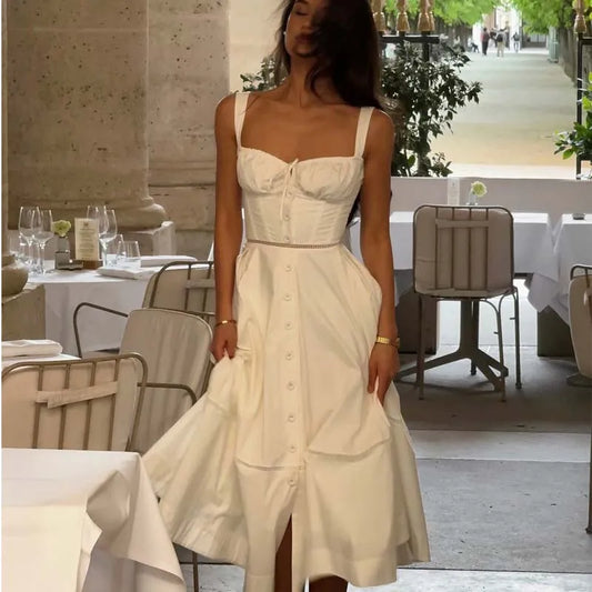 Woman in a white dress standing in an outdoor dining area.