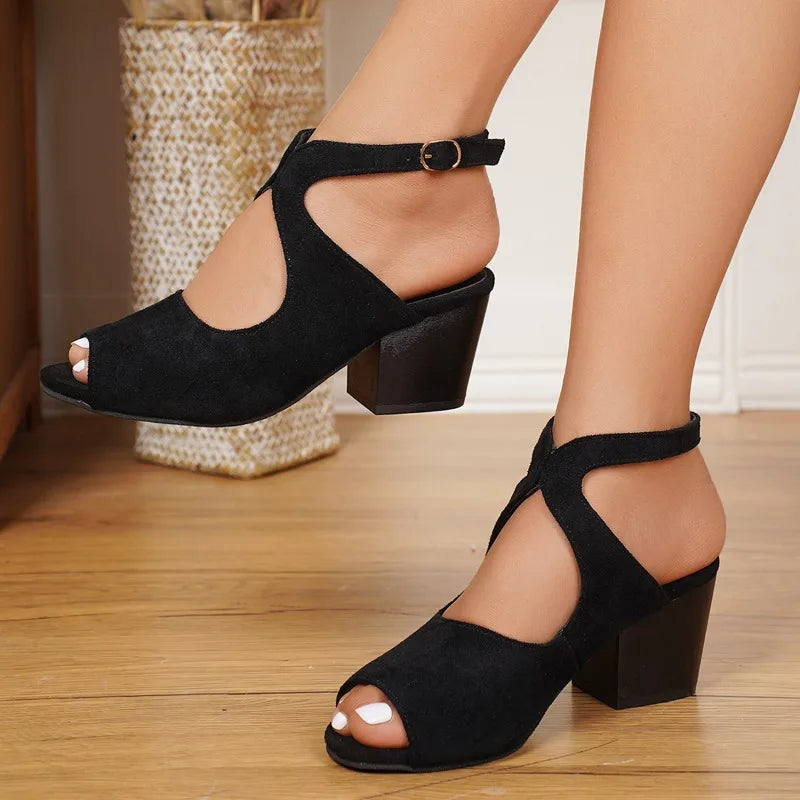 Black open-toe high-heeled shoes on a wooden floor