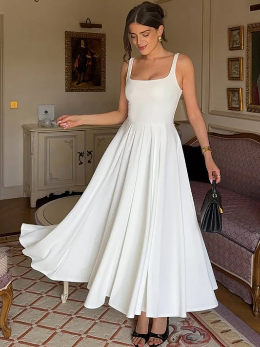 Woman in a white dress standing in an elegant room with decorative elements.