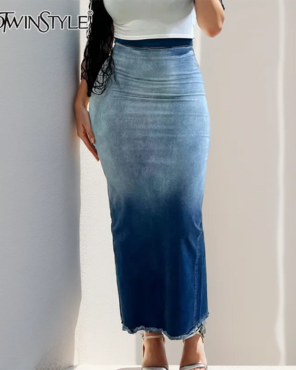 Person wearing a long denim skirt with a plain background, featuring the brand 'TWOFTWISTYLE'.