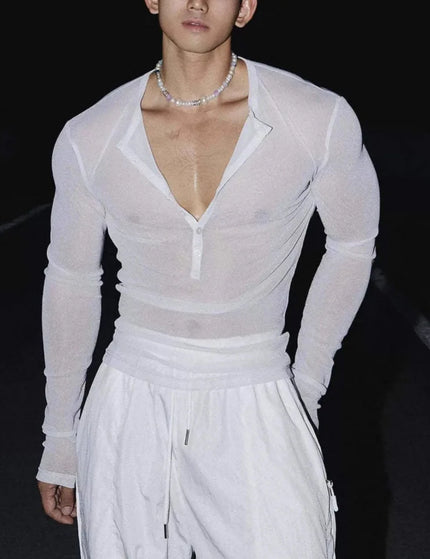 Person wearing a sheer white long-sleeve top and white pants on a dark background