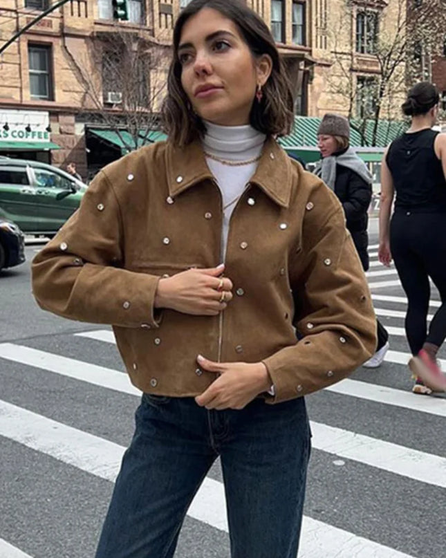 Woman wearing a brown jacket with pearl embellishments on a city street.