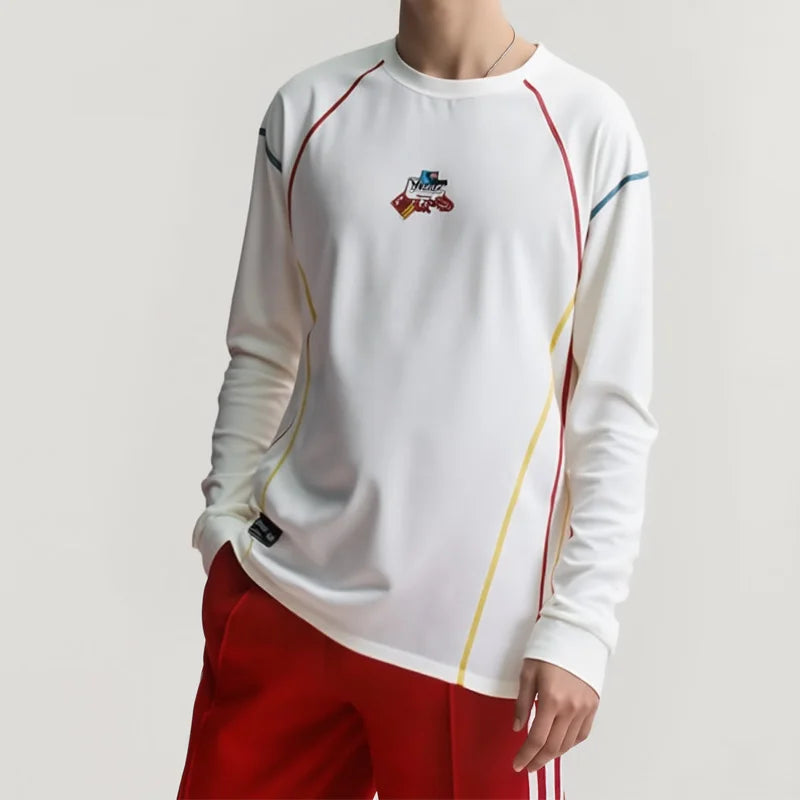 White long-sleeve athletic shirt with colorful accents and red shorts on a plain background