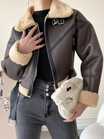 Person wearing a brown leather jacket with beige fur lining, holding a white bag.
