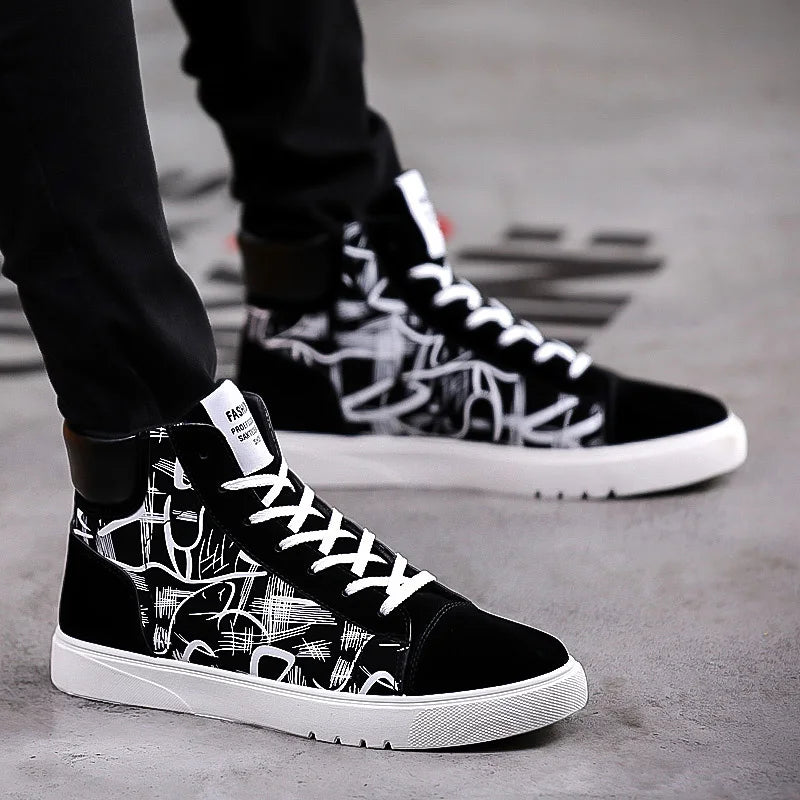 Black high-top sneakers with white graphics worn by a person on a concrete surface