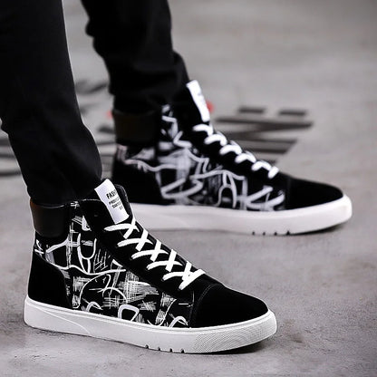 Black high-top sneakers with white graphics worn by a person on a concrete surface