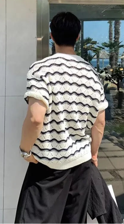 Person wearing a black and white striped shirt standing in front of a glass door.