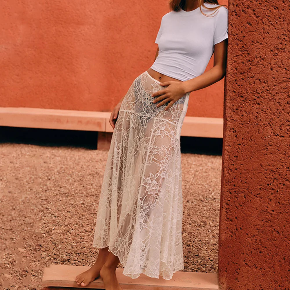 Woman wearing a white lace skirt and crop top against a textured wall.