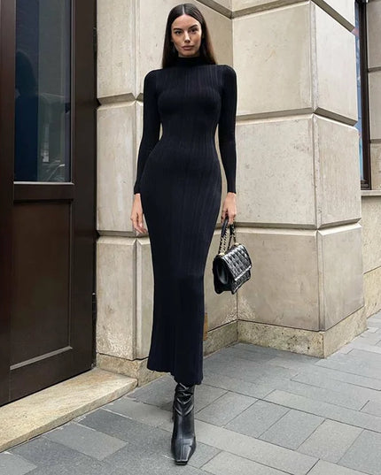 Woman in a black dress standing against a building wall