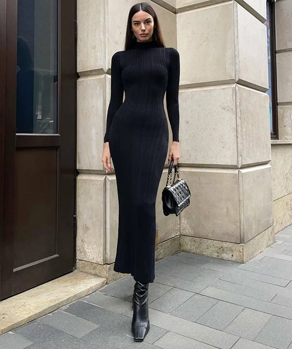 Woman in a black dress standing against a building wall