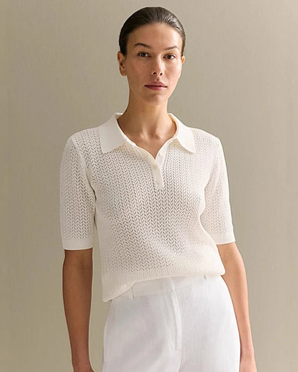 Woman wearing a white knit top and white pants against a beige background
