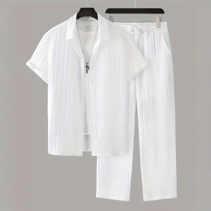 White pleated shirt and pants set on hangers against a gray background