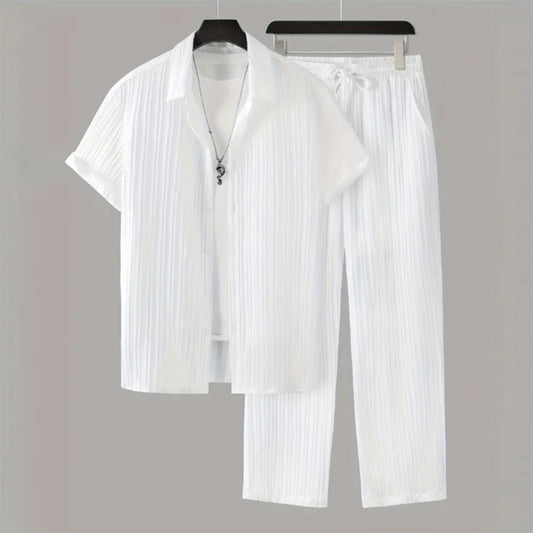 White pleated shirt and pants set on hangers against a gray background
