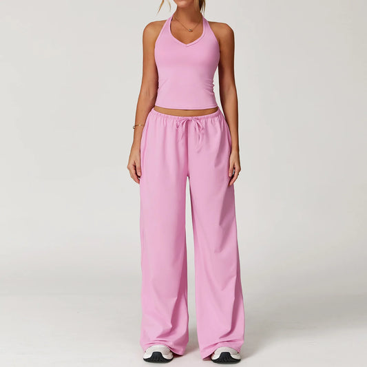 Person wearing a pink outfit with a top and wide-leg pants on a white background