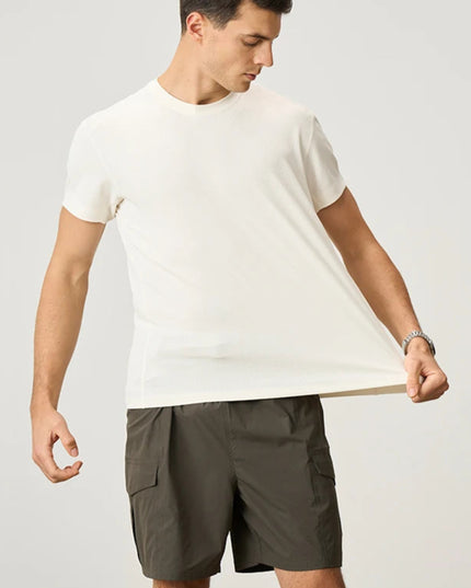 Man wearing a white t-shirt and green shorts on a plain background