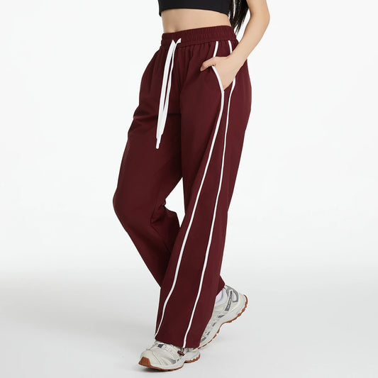 Maroon track pants with white stripes worn by a person on a white background