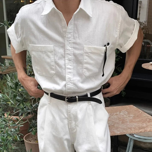 Person wearing a white shirt and pants with a black belt outdoors.