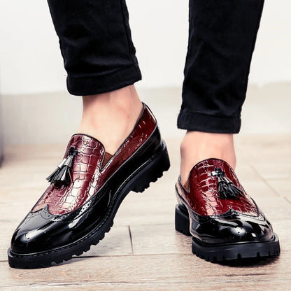 Red leather loafers with black soles and tassels on a light wooden floor.