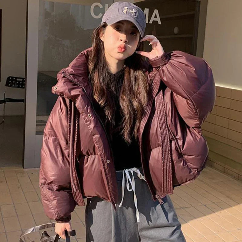 Person wearing a large pink puffer jacket and gray cap outdoors.