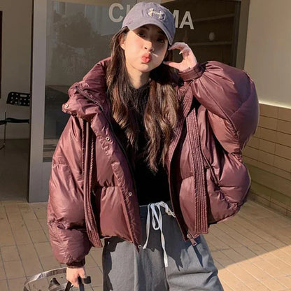 Person wearing a large pink puffer jacket and gray cap outdoors.