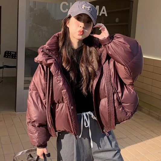 Person wearing a large pink puffer jacket and gray cap outdoors.