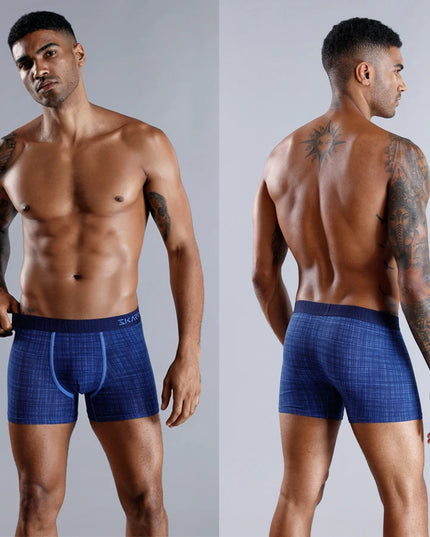Man wearing blue boxer briefs on a gray background