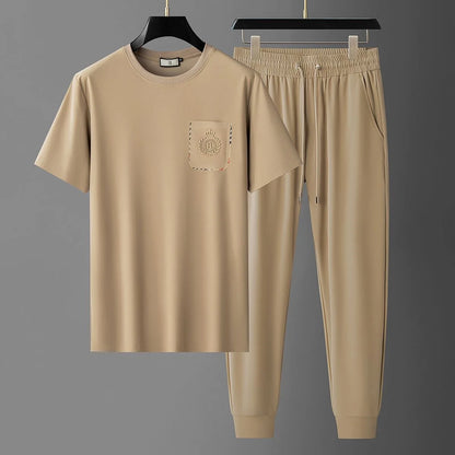 Beige t-shirt and pants set on hangers against a gray background