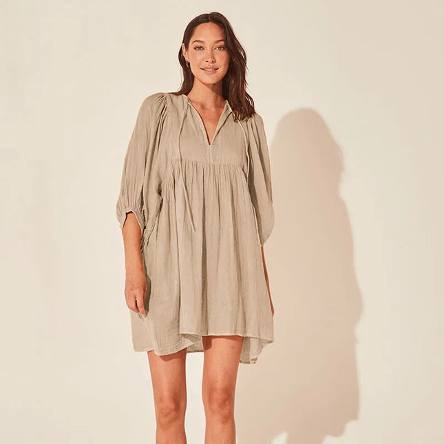 Woman wearing a beige dress against a plain background