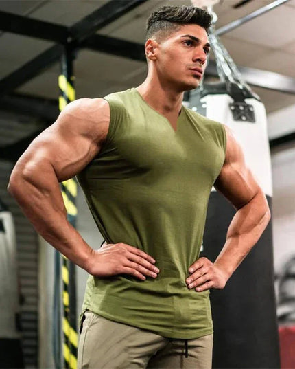 Muscular man in a green tank top posing in a gym setting