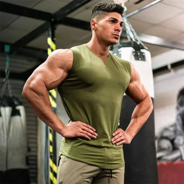 Muscular man in a green tank top posing in a gym setting