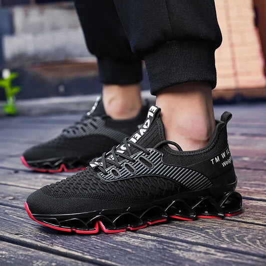 Black athletic shoes with red soles worn by a person on a wooden floor.