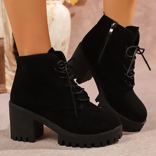 Black suede platform boots with chunky soles on a neutral background